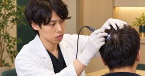 医師が頭皮用のマイクロスコープを患者さんの頭頂部に当てて、頭皮の状態を確かめている様子